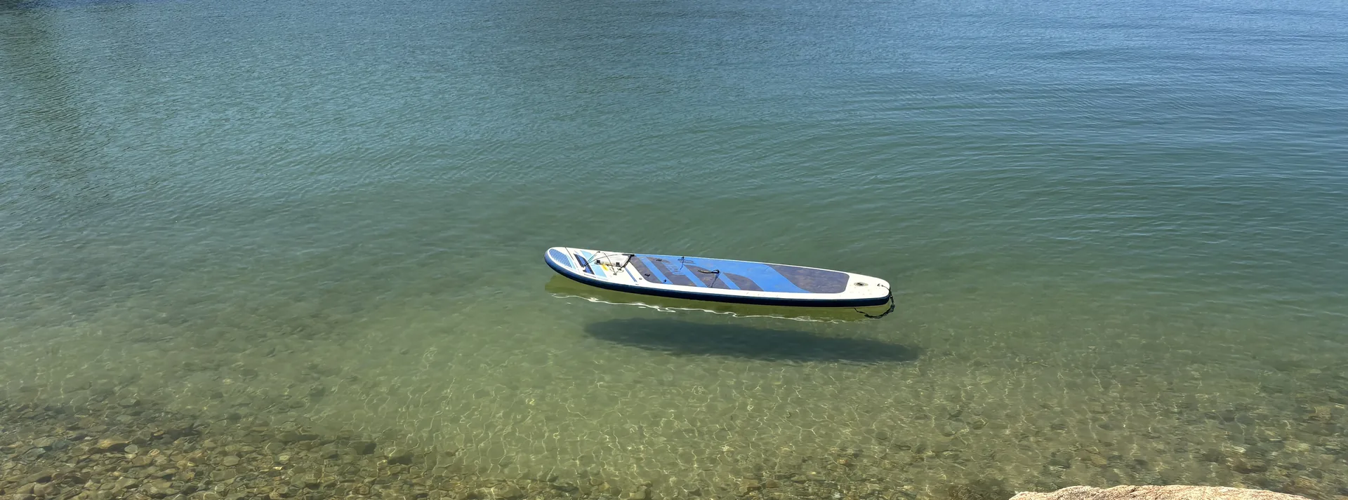 A paddleboard floating on the glass-clear water of Whiskeytown Lake near Redding, California