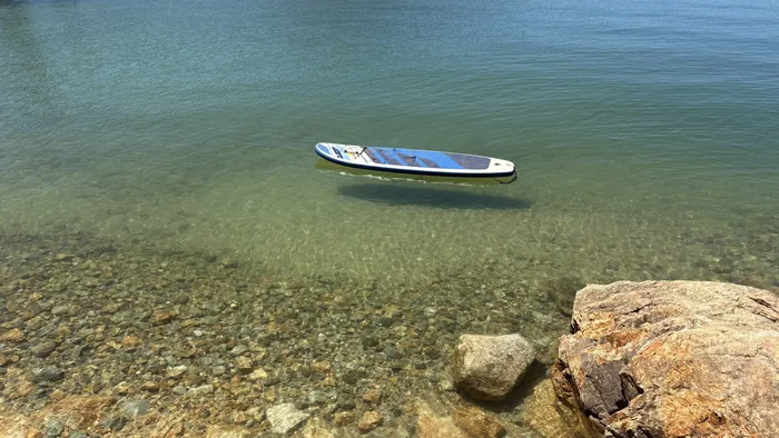 A paddleboard floating on glass-clear water at Whiskeytown Lake
